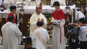 Bishop praying over Fr Anthony Liew