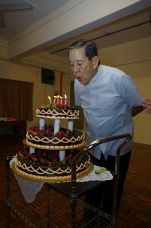 Fr Robin blowing out candles on cake