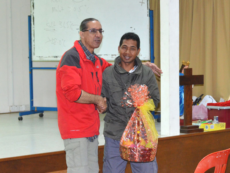 Kg Sekam's Bah Jalil presenting basket to Dr Amar