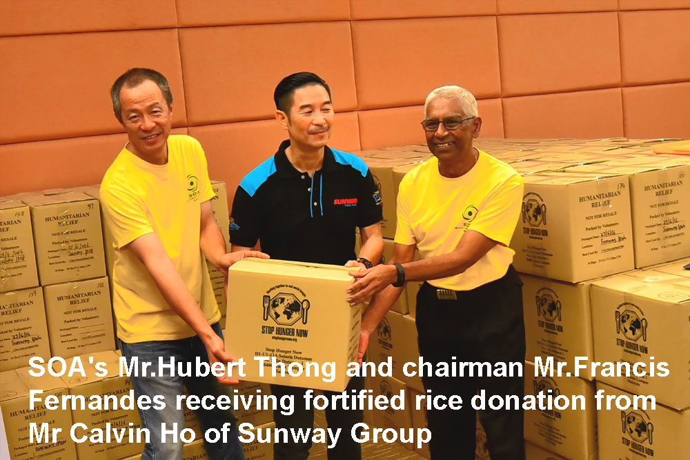 Hubert Thong and Francis Fernandes receive rice packs from Sunway's Calvin Ho
