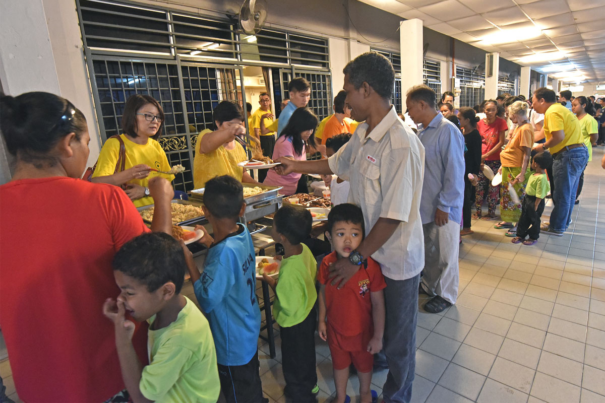 SOA members and Chinese Apostolate serve dinner to orang asli at parish hall