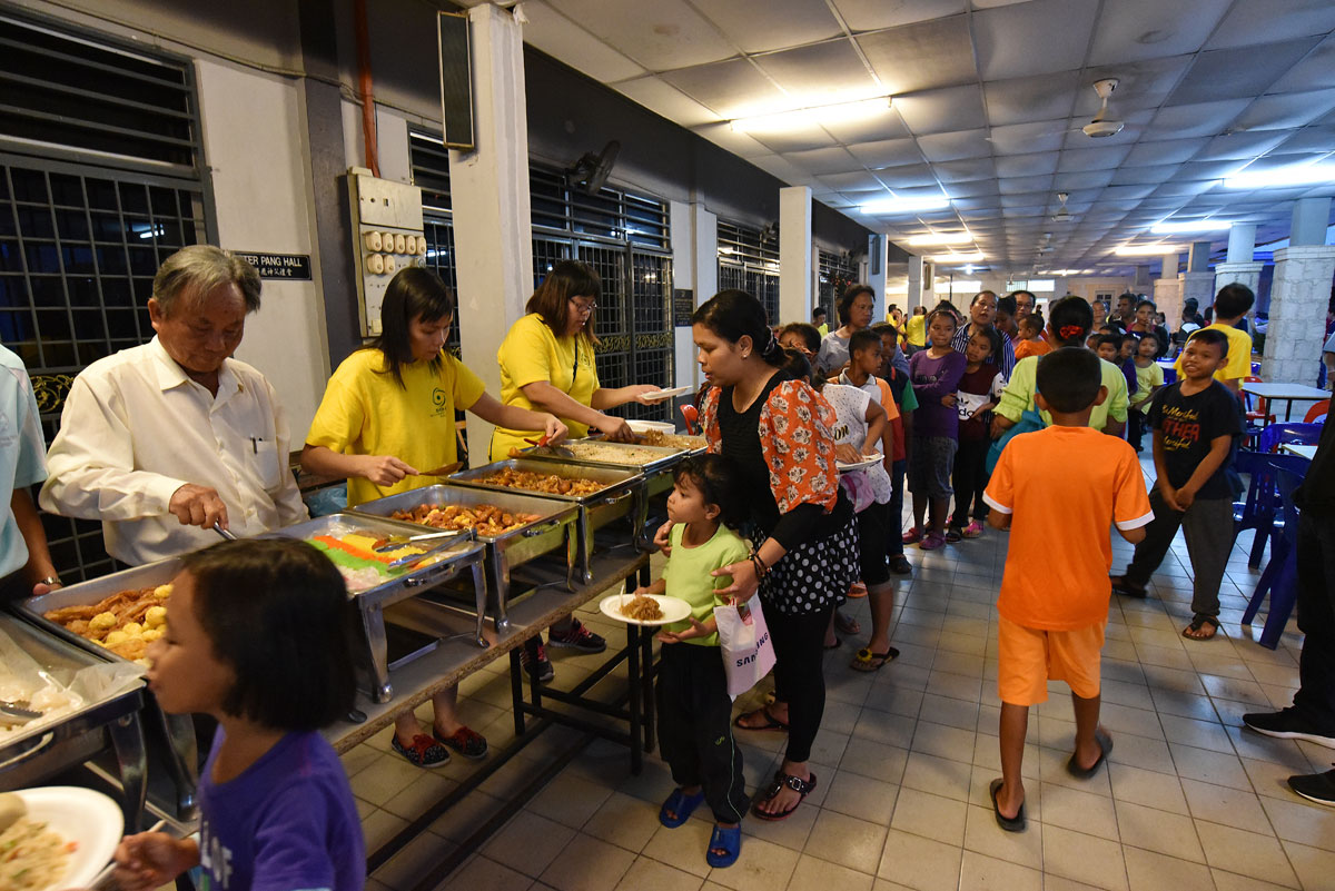 Chinese Apostolate and SOA members serve dinner to orang asli at parish hall